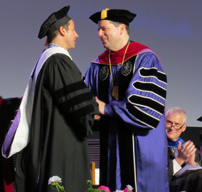 Raine Maida shakes hands with the Rev. James J. Maher, C.M., president of Niagara University.