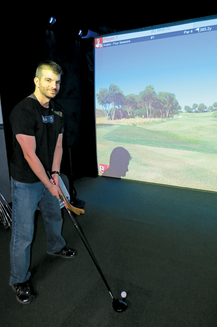 Jonathan Simon plays the golf simulator at Lewiston Event Center.