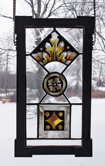 Stained-glass artwork decorates a window of Roswell Pfohl daughter Peggy Bauman's home on East River Road. The artwork is comprised of salvaged glass from the aftermath of a fire at St. Michael's Church in downtown Buffalo. Bauman's father designed the new altar when the church was rebuilt. (Photo by Karen Keefe)