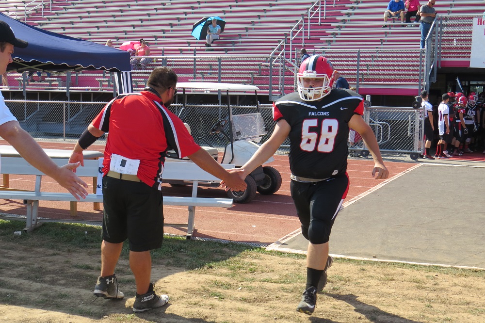 Lineman Jake Ambrosia shakes Coach Russ Nixon's hand as he takes the field.