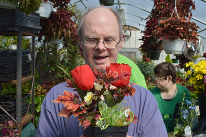 Ricky Koban shows off an arrangement he just finished. Connie Greer works on a floral arrangement.